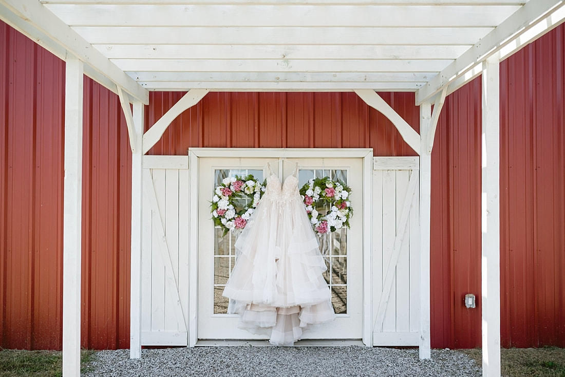 wedding dress from the barefoot bride hanging on the doors of the barn  at the wedding barn in arkansas