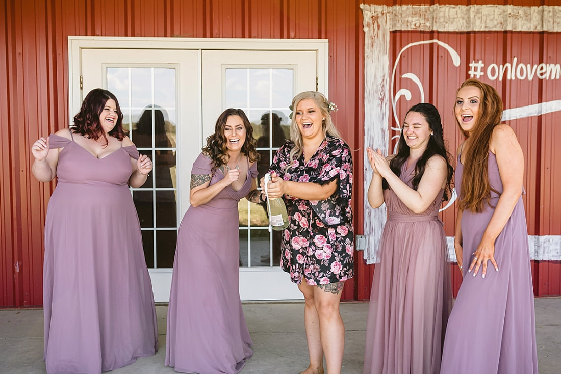 bride popping champagne at the wedding barn in arkansas