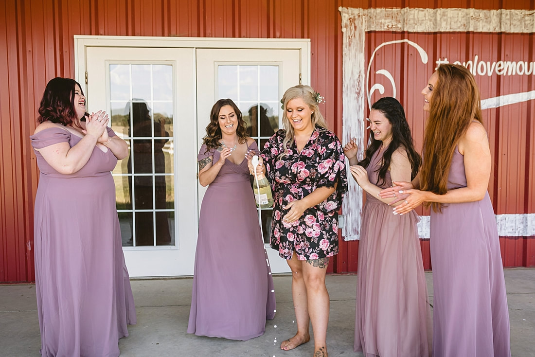 girls popping champagne at the wedding barn in arkansas