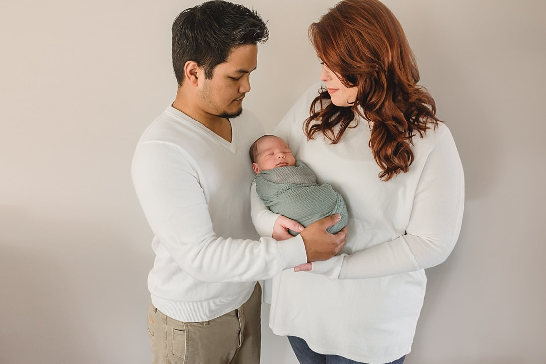 new family of three, mom and dad holding newborn baby boy during newborn photos in memphis, tn
