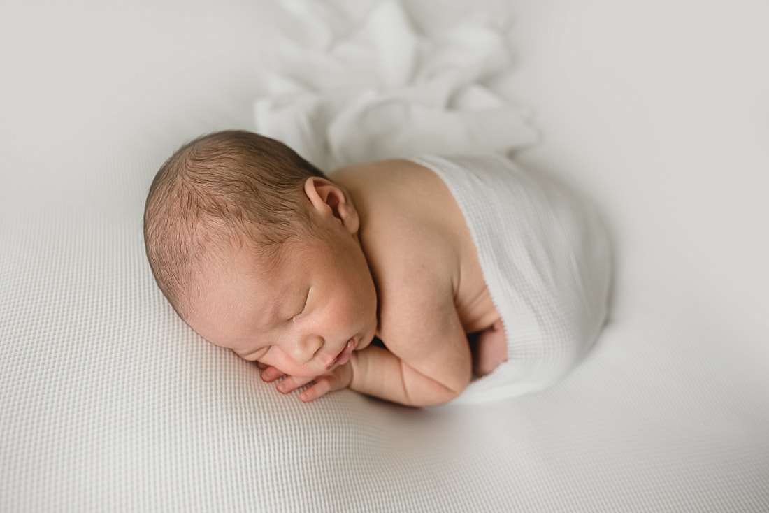 cute newborn baby boy wrapped in white for newborn photo shoot in memphis