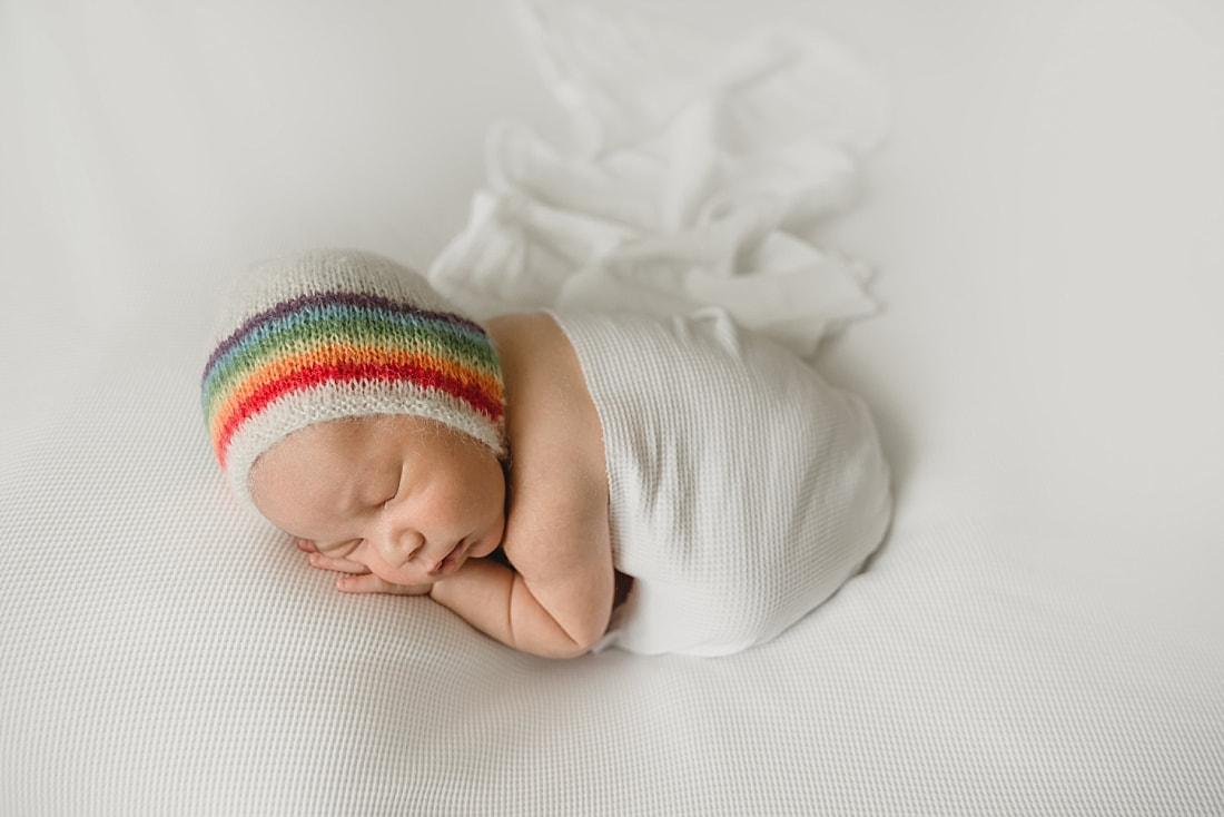 rainbow baby boy wearing rainbow bonnet for newborn photo shoot in memphis