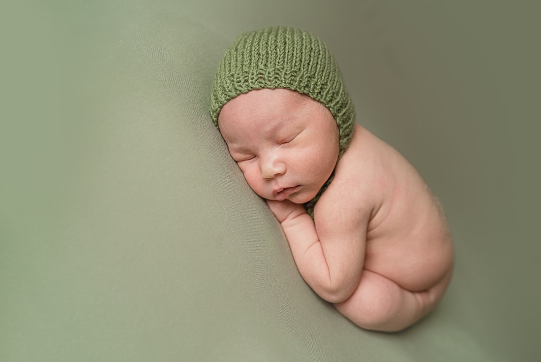 adorable newborn baby boy wearing green bonnet during newborn photo shoot in memphis