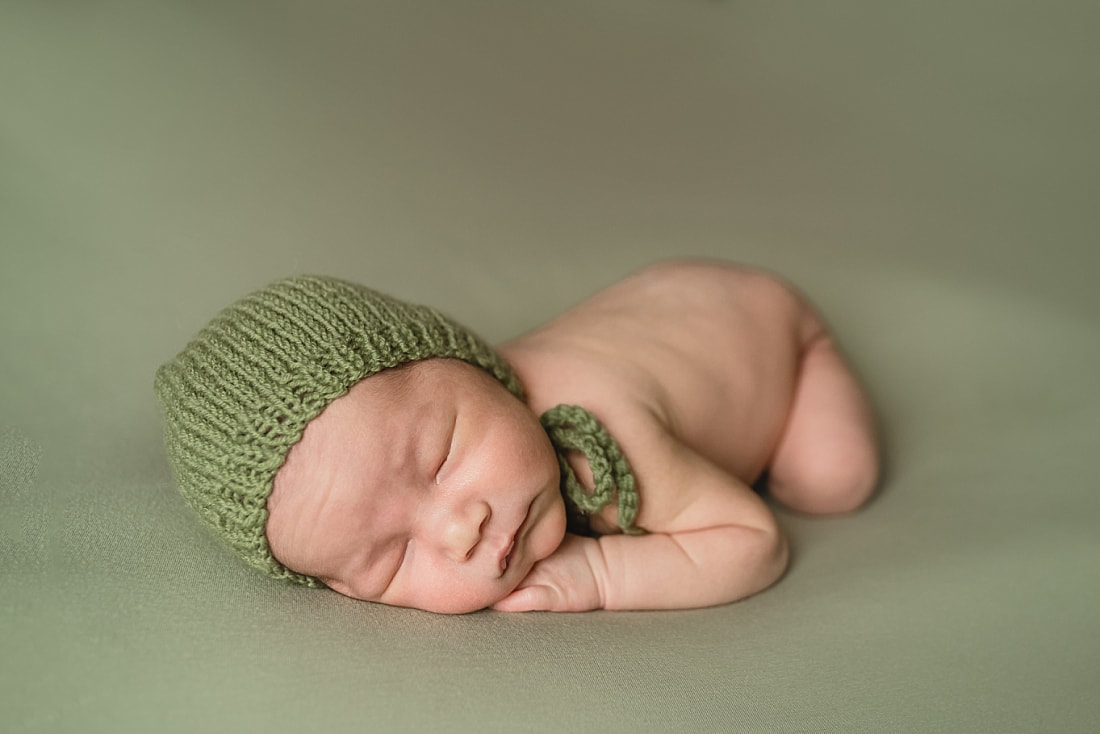 adorable newborn baby boy wearing green bonnet during newborn photo shoot