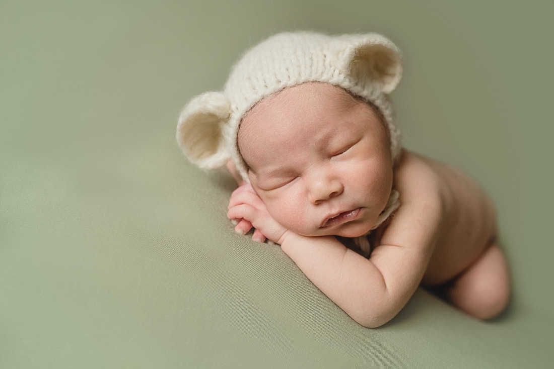 adorable newborn baby boy wearing teddy bear bonnet during newborn photo shoot