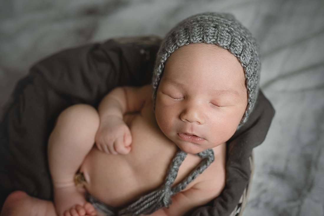 adorable newborn baby boy wearing a gray bonnet during newborn photo shoot in memphis