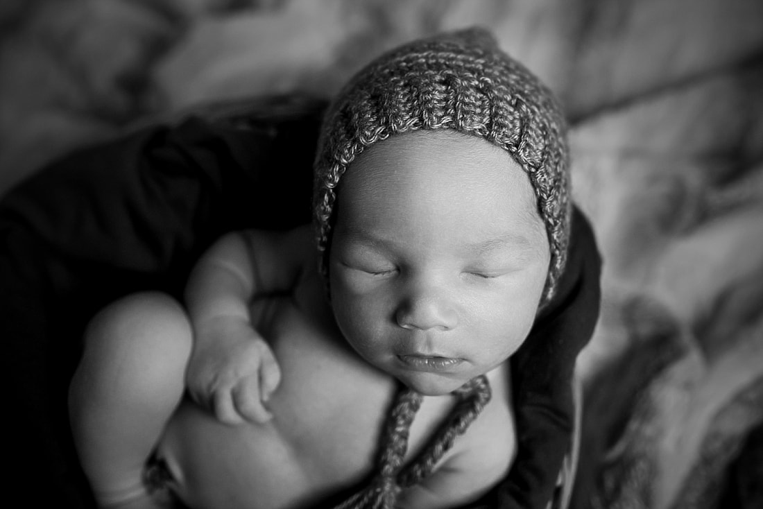 adorable newborn baby boy wearing a gray bonnet during newborn photo shoot