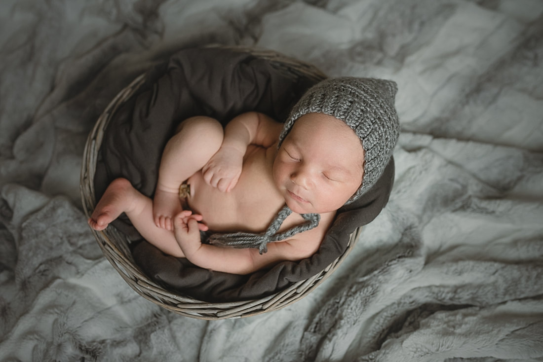 adorable newborn baby boy wearing a gray bonnet during newborn photo shoot