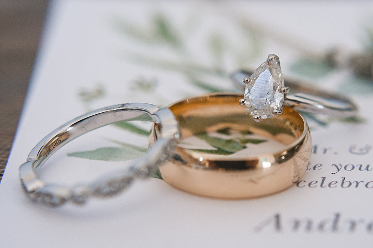 close up photo of wedding rings with a teardrop shaped diamond