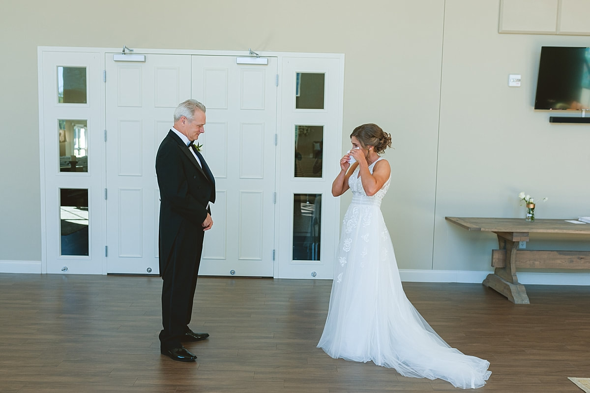 bride wiping away her tears at her first look with her father