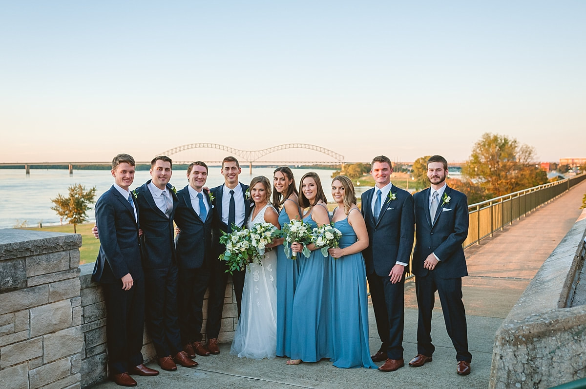 bride and groom with their wedding party in front of the m bridge over the mississippi river downtown memphis