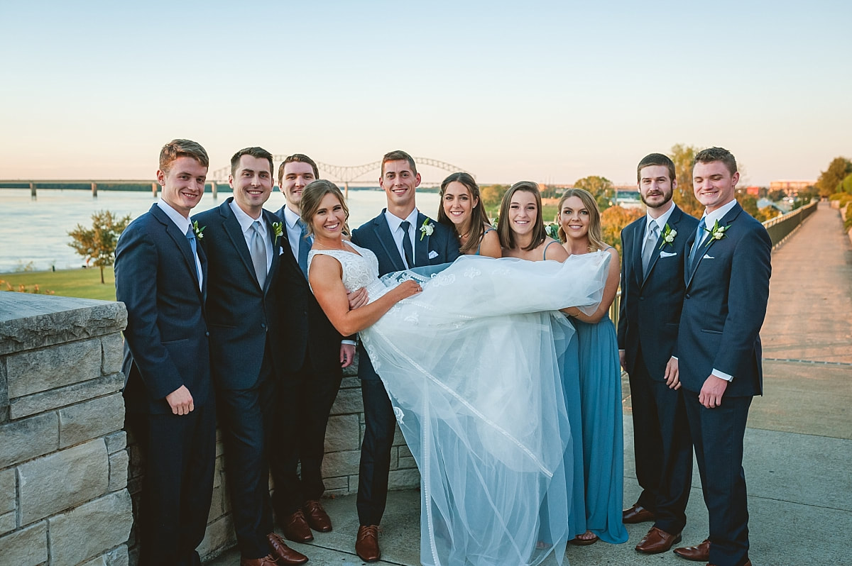 bride and groom with their wedding party in front of the m bridge over the mississippi river downtown memphis
