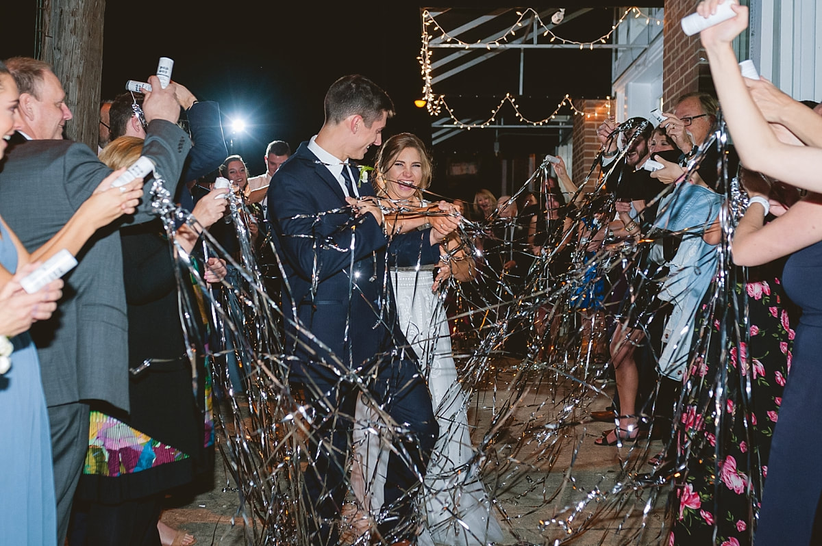 bride and groom exiting their wedding reception as wedding guests shoot confetti at them at the robinson gallery downtown memphis