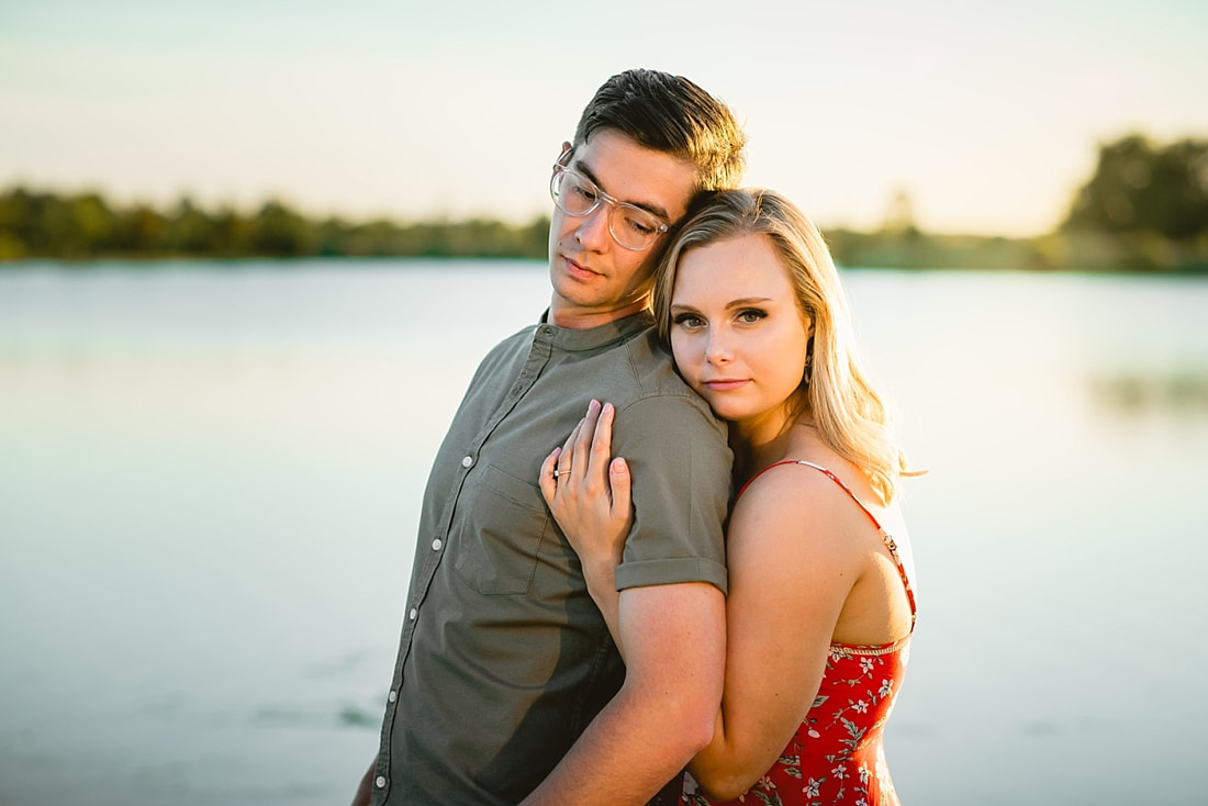 couple posing for engagement photos by the lake at shelby farms park in memphis, tn