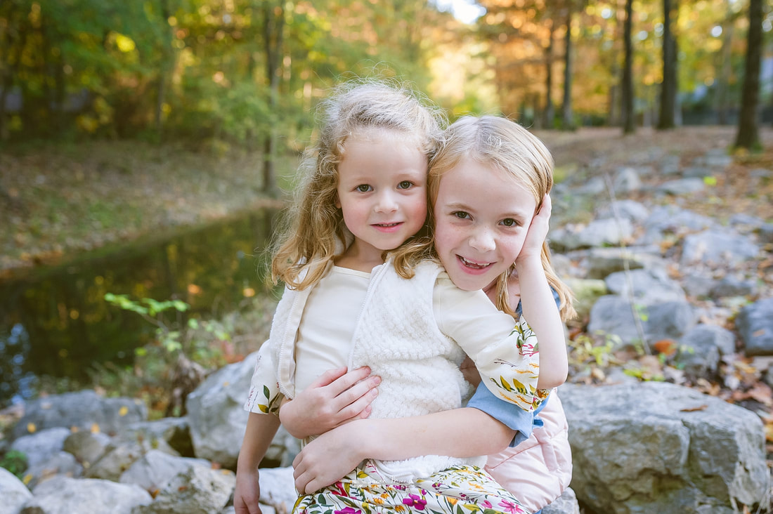 sisters snuggled up next to the creek during fall mini session