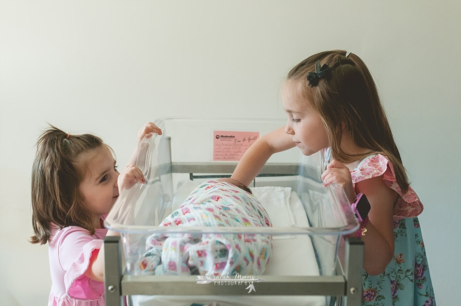 big sisters admiring their newborn baby sister in her bassinet at Methodist Le Bonheur Germantown Hospital