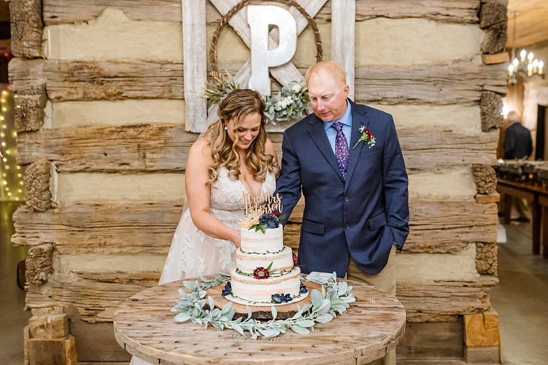 bride and groom cutting wedding cake during barn wedding reception at Green Frog Farm