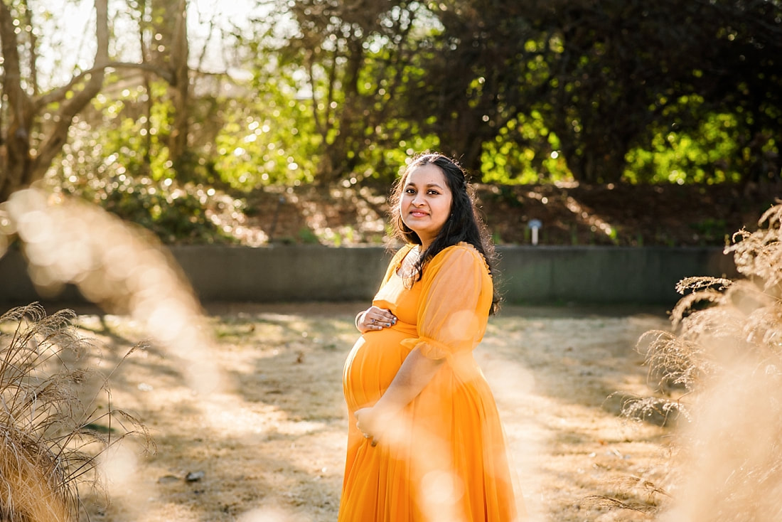 beautiful pregnant lady wearing orange dress at memphis botanic garden