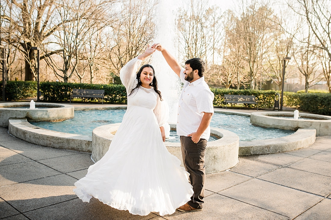 father and mother dancing by the fountain during maternity photo session at memphis botanic garden