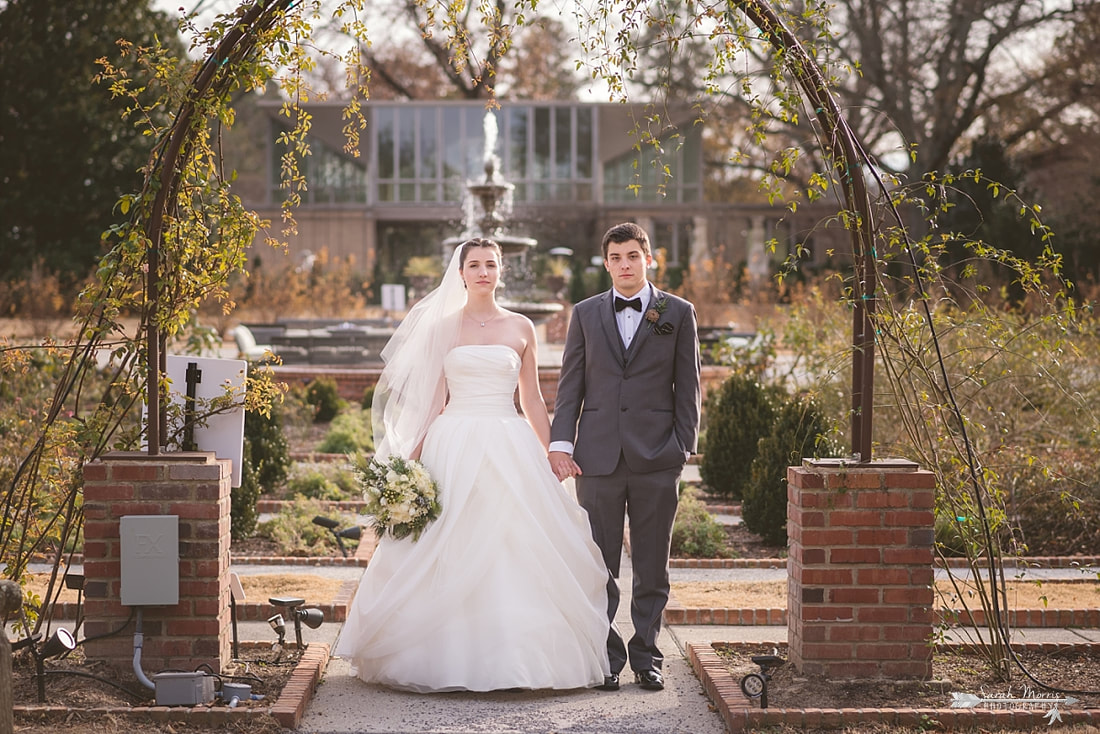 bride and groom holding hands under trellis in the rose garden at memphis botanic garden