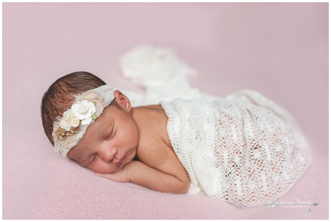 newborn photos of baby girl on pink blanket wearing flower headband