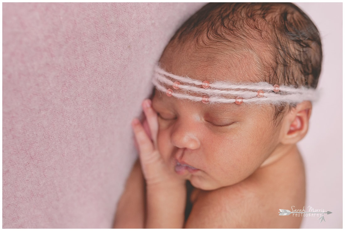 newborn photos of baby girl on pink blanket wearing pink headband