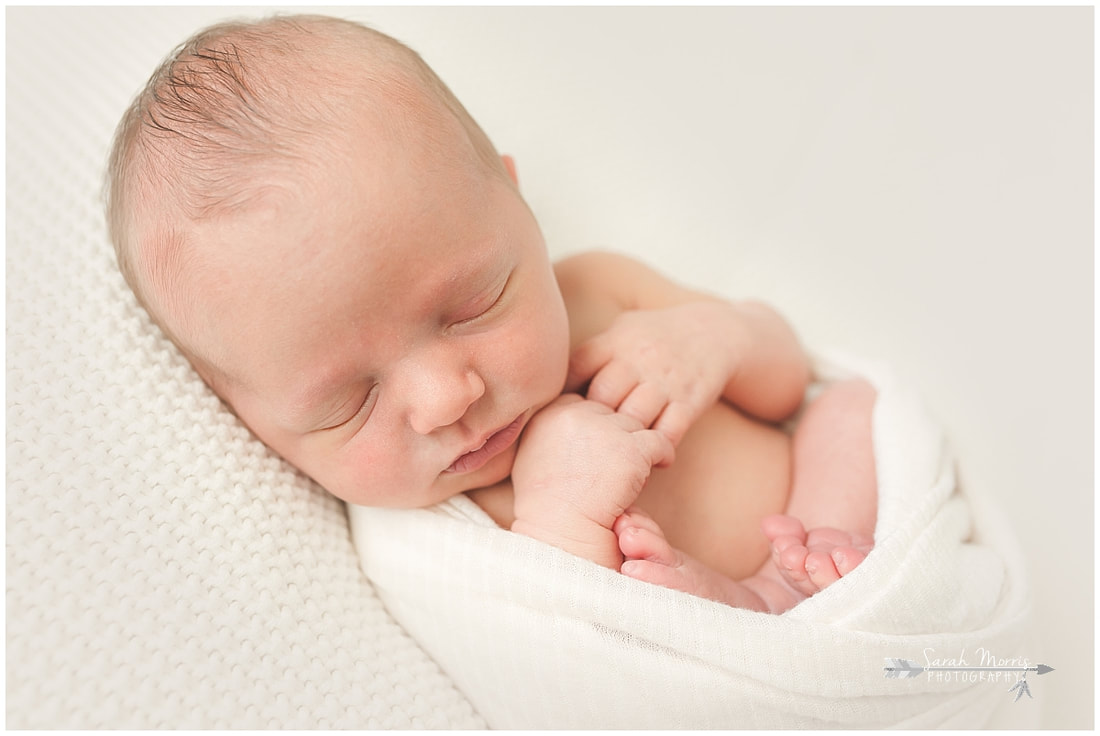 Newborn photo of baby boy sleeping on white blanket