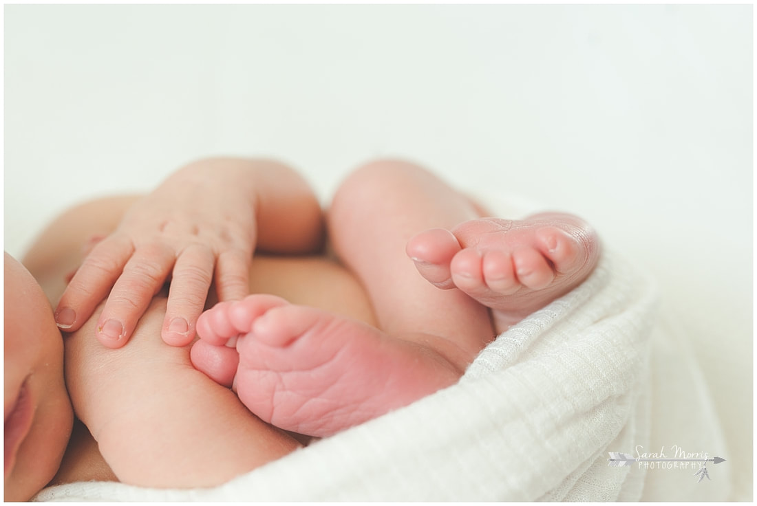 Newborn photo of baby boy sleeping on white blanket close up of feet and hands