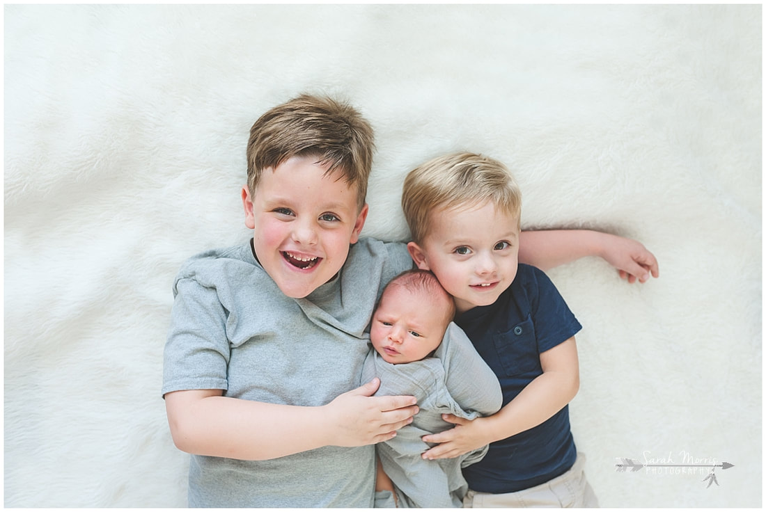 Newborn photos with older siblings on fur rug