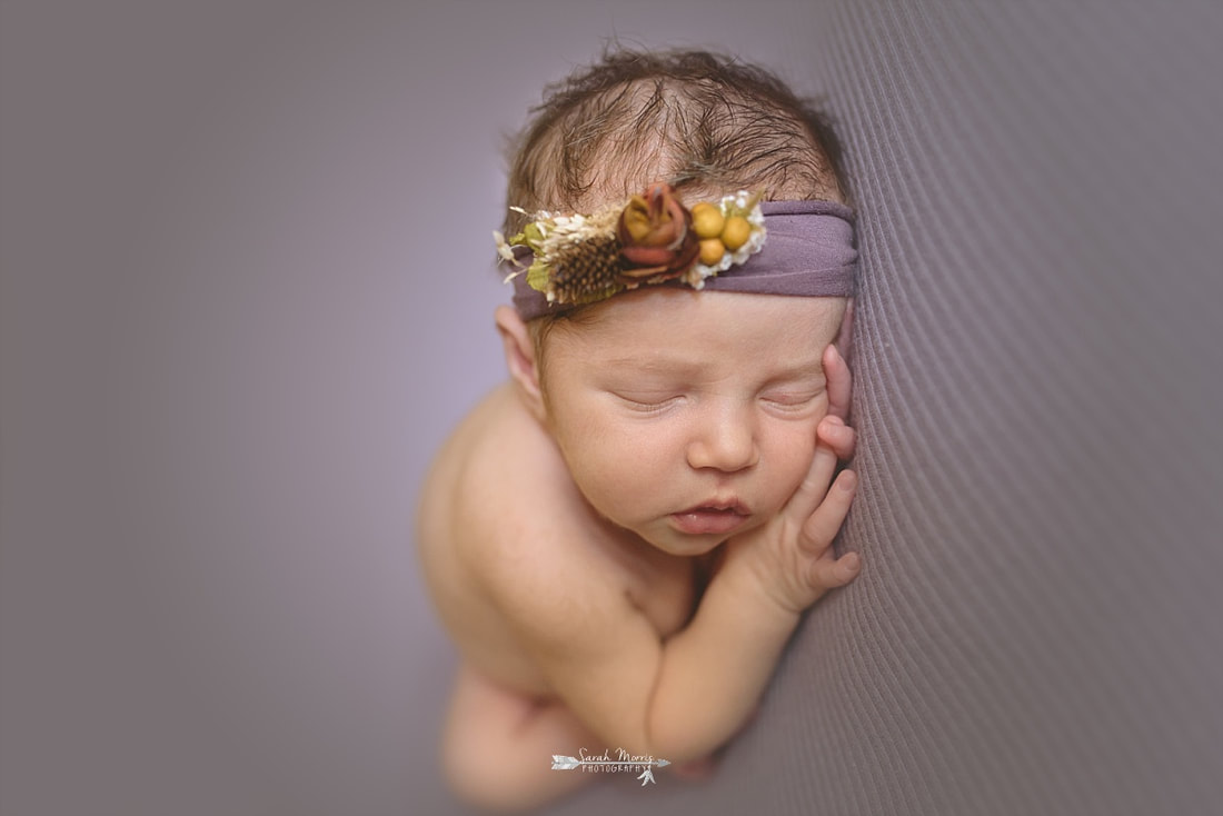 newborn baby girl sleeping on a purple blanket, wearing a purple flower crown