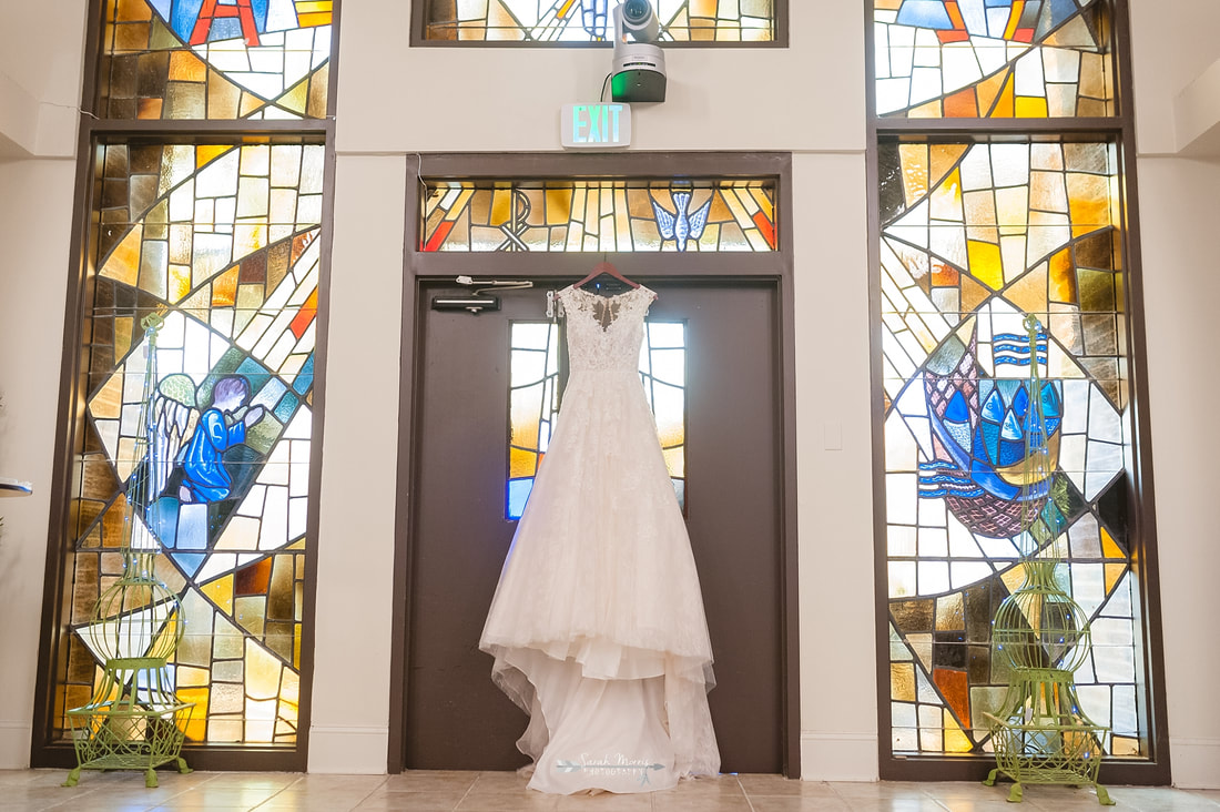 Wedding dress hanging in front of stained glass window at Overton Chapel, Memphis Wedding Photographer