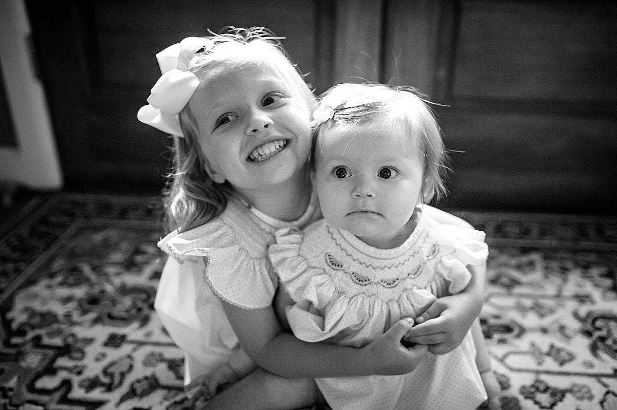 black and white photo of sisters in matching smocked dresses during in home lifestyle family session in collierville, tn