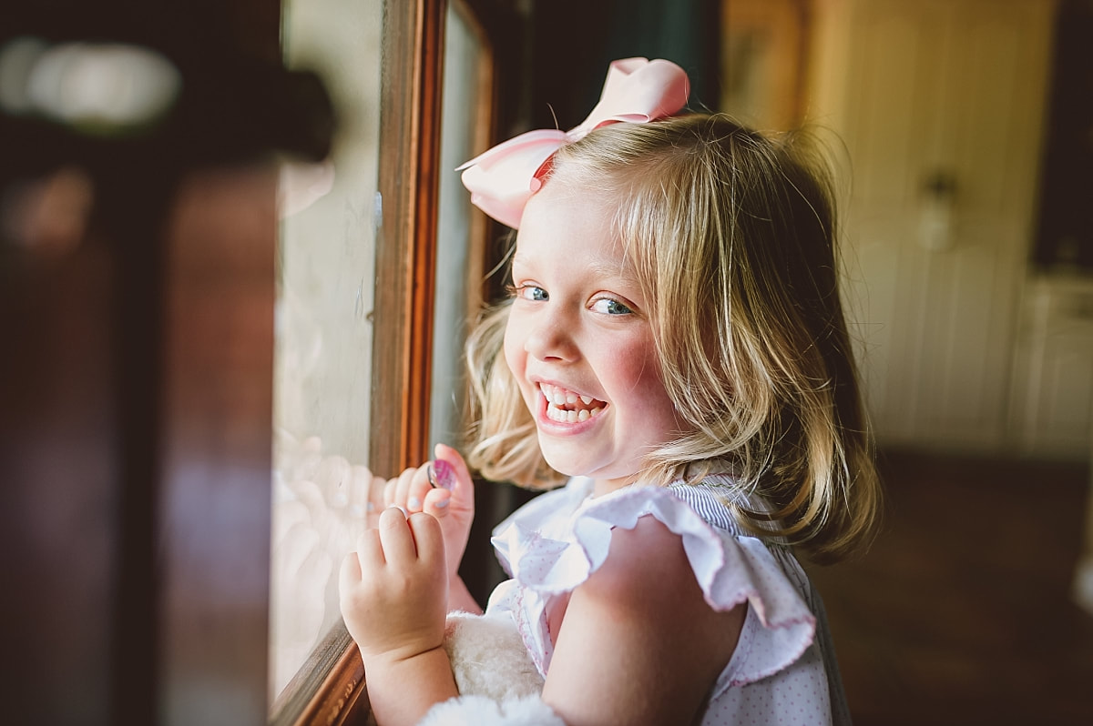little girl staring out the window during in home lifestyle family session in colliervill, tn