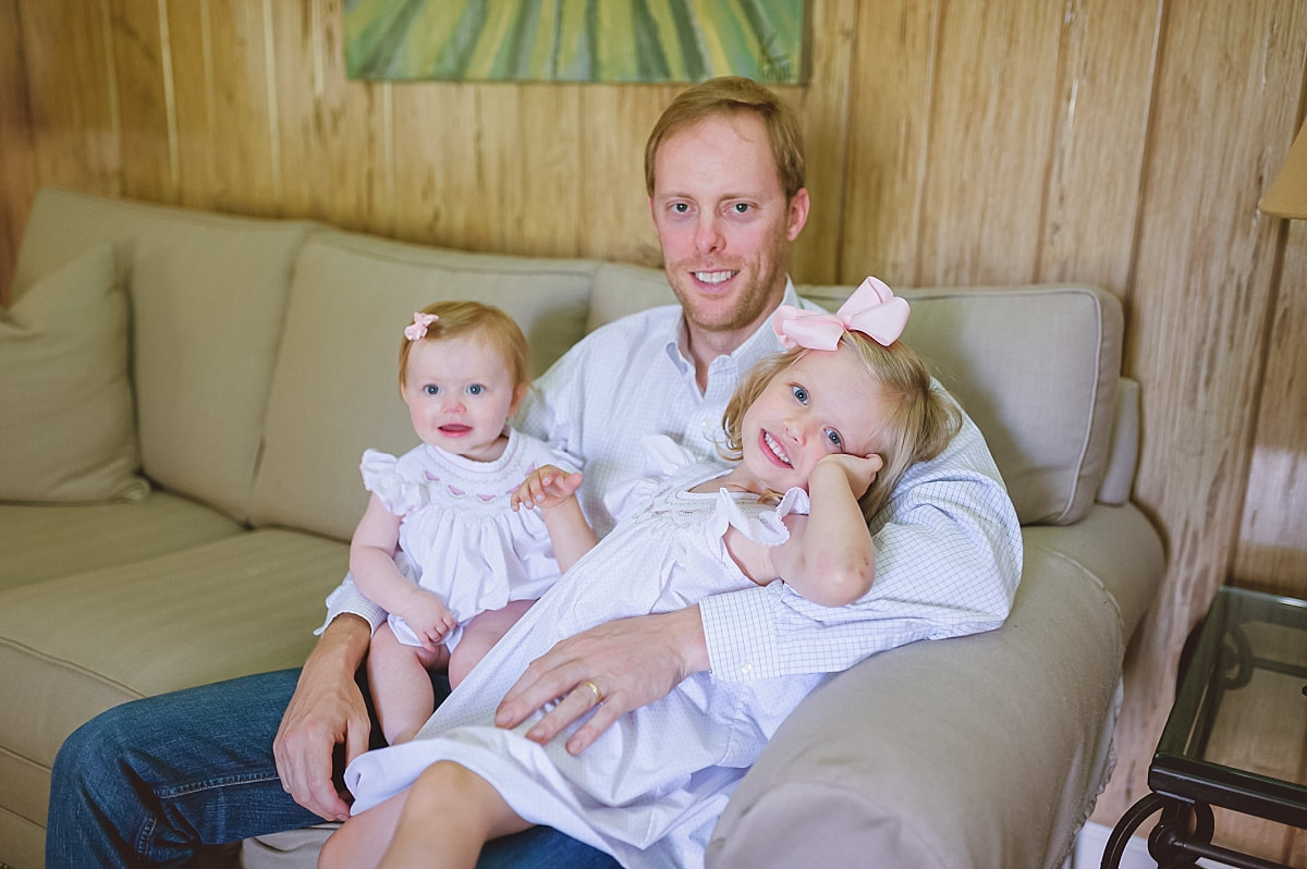 father holding his baby girls on the couch during in home lifestyle family session in collierville, tn