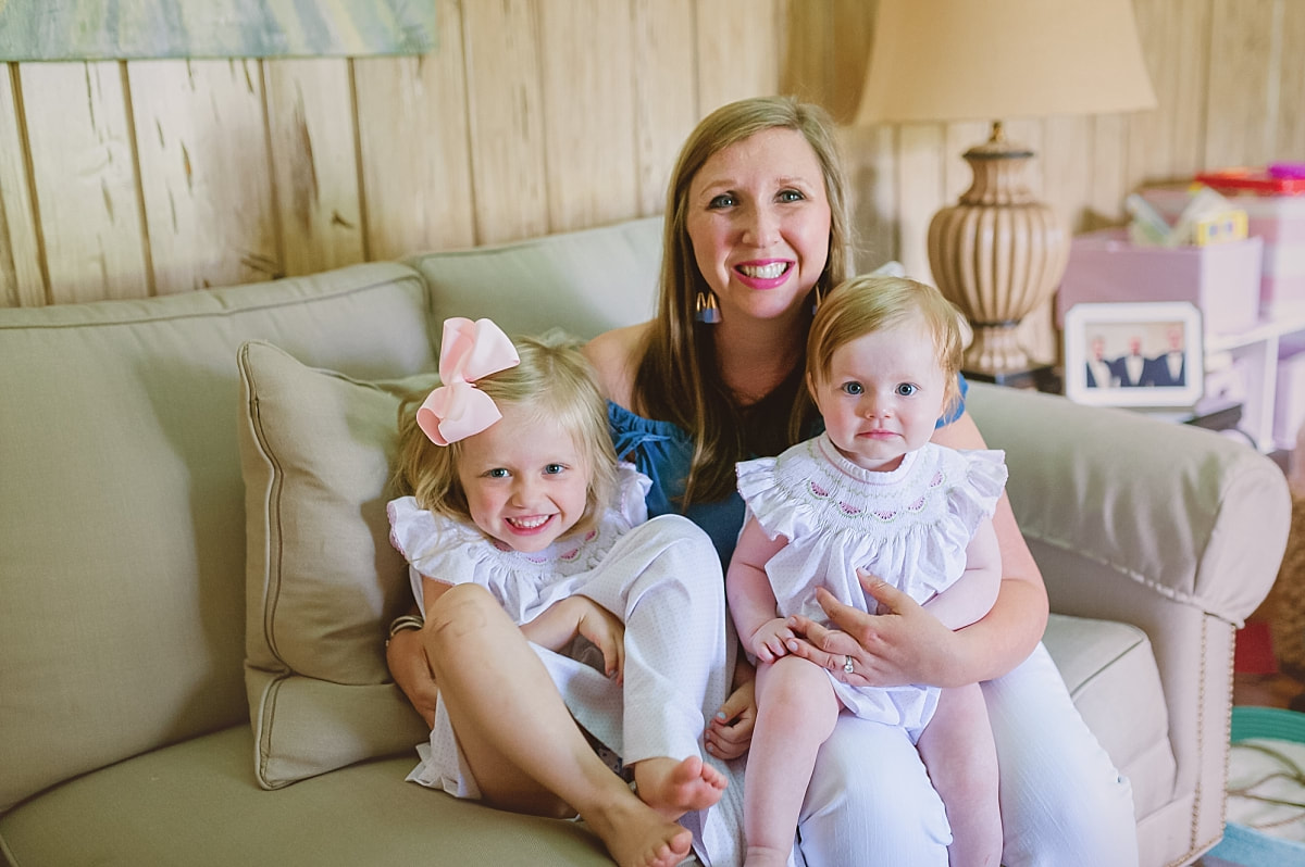 mother holding her daughters on the couch during in home lifestyle family session in collierville, tn
