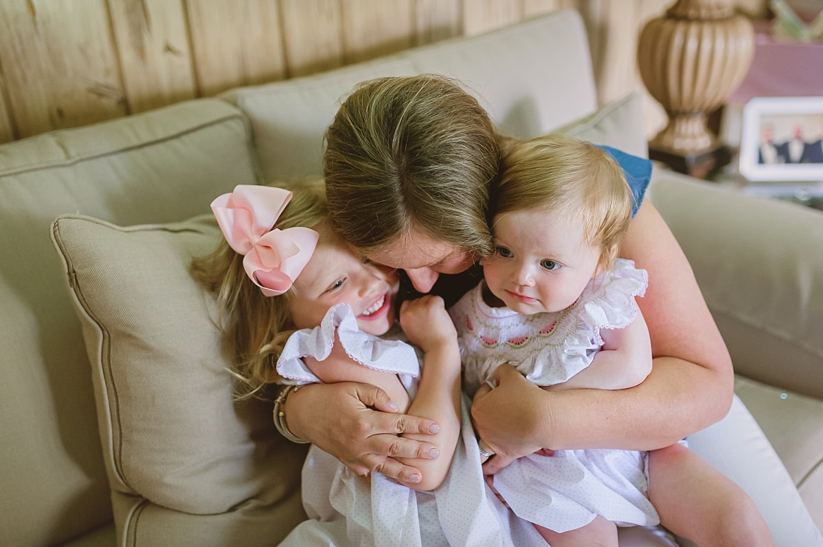 mother snuggling her daughters on the couch during in home lifestyle family session in collierville, tn
