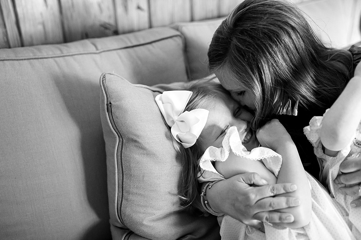 black and white close up of mother kissing and snuggling her daughter on the couch during in home lifestyle family session in collierville, tn