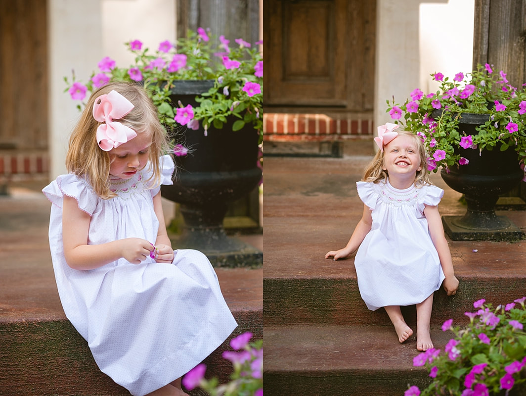 little girl in a classic smocked dress on next to purple flowers during in home lifestyle family session in collierville, tn