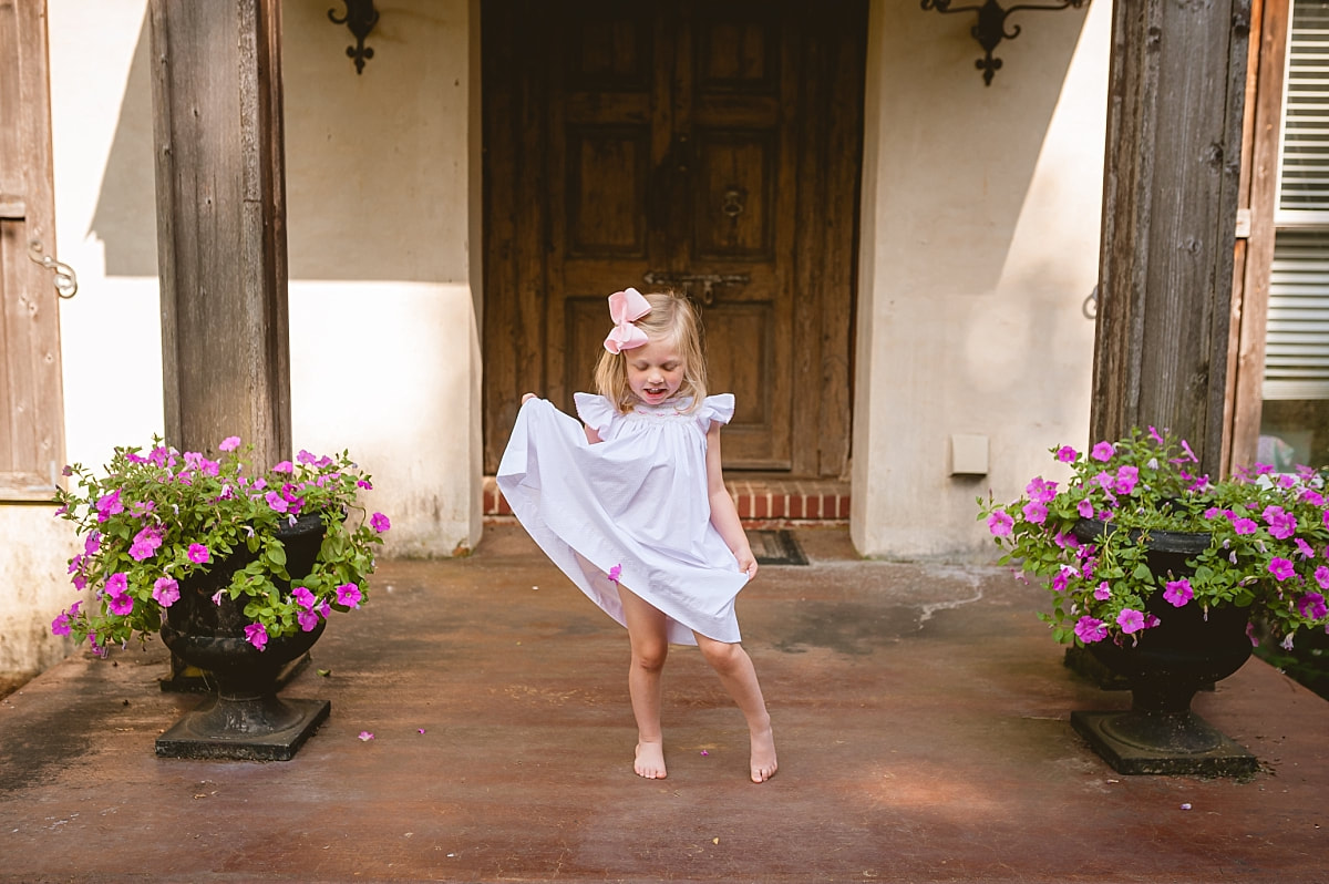 little girl twirling in her classic smocked dress on the front porch during in home lifestyle family session in collierville, tn