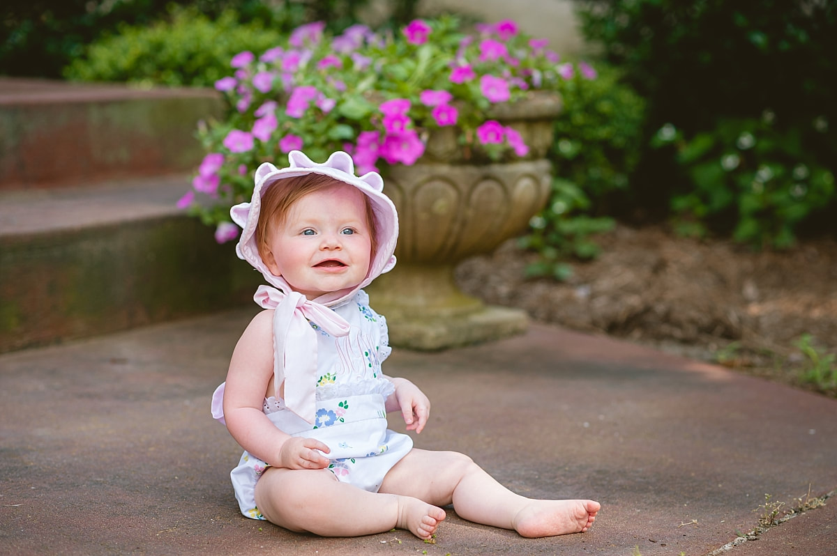 baby girl's first birthday portrait, wearing a monogrammed bubble and Beaufort bonnet on the front porch during in home lifestyle family session in collierville, tn
