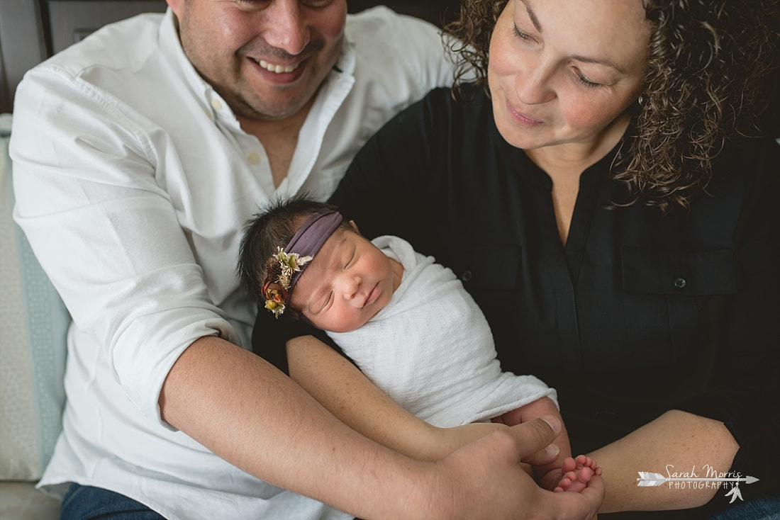 Family cuddled up on bed with newborn baby sister for the lifestyle portion of her newborn photo session