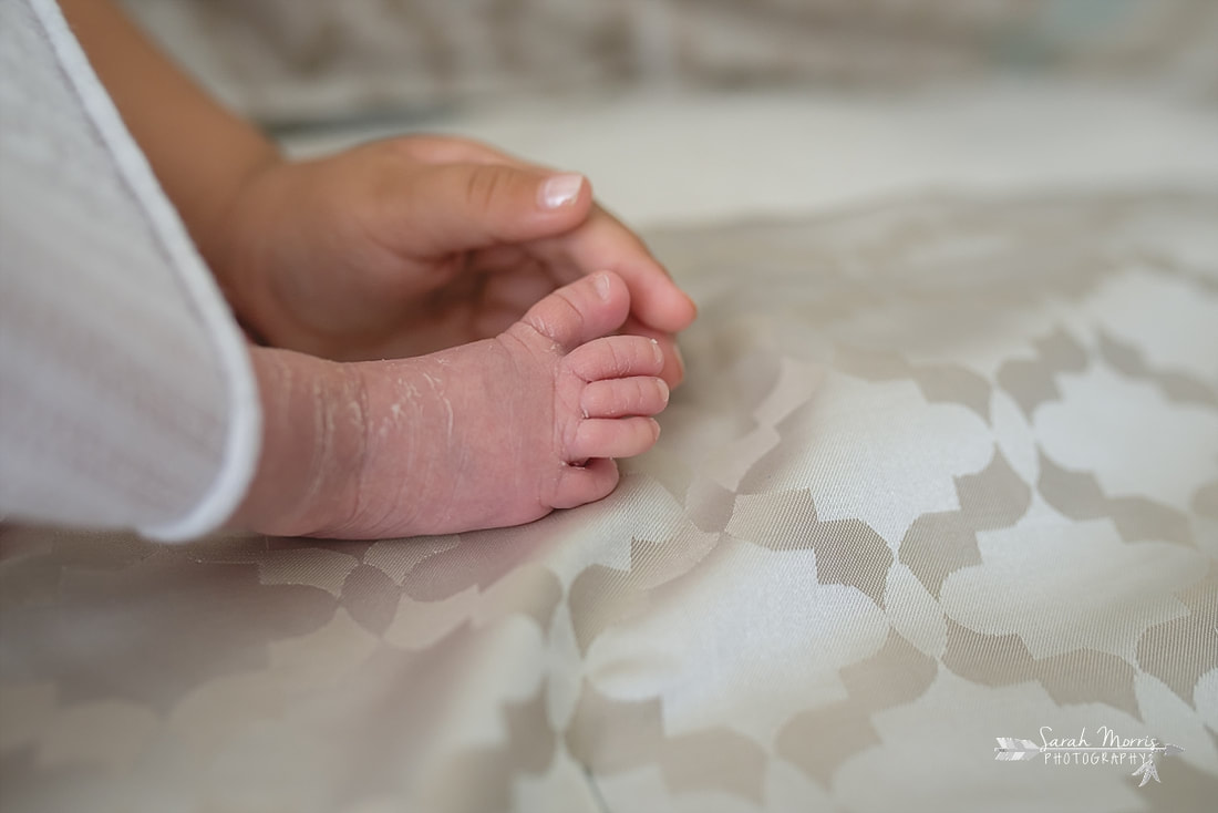 Close up of big sister holding baby sister's foot during the lifestyle portion of her newborn photo session