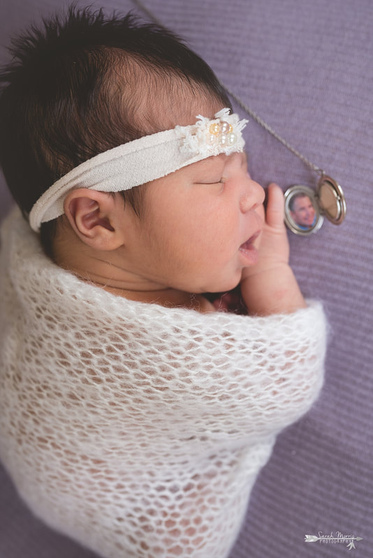 Newborn baby girl wearing a cream headband with pearls and wrapped in a beautiful soft cream knit blanket sleeping on purple blanket during the posed portion of her newborn session
