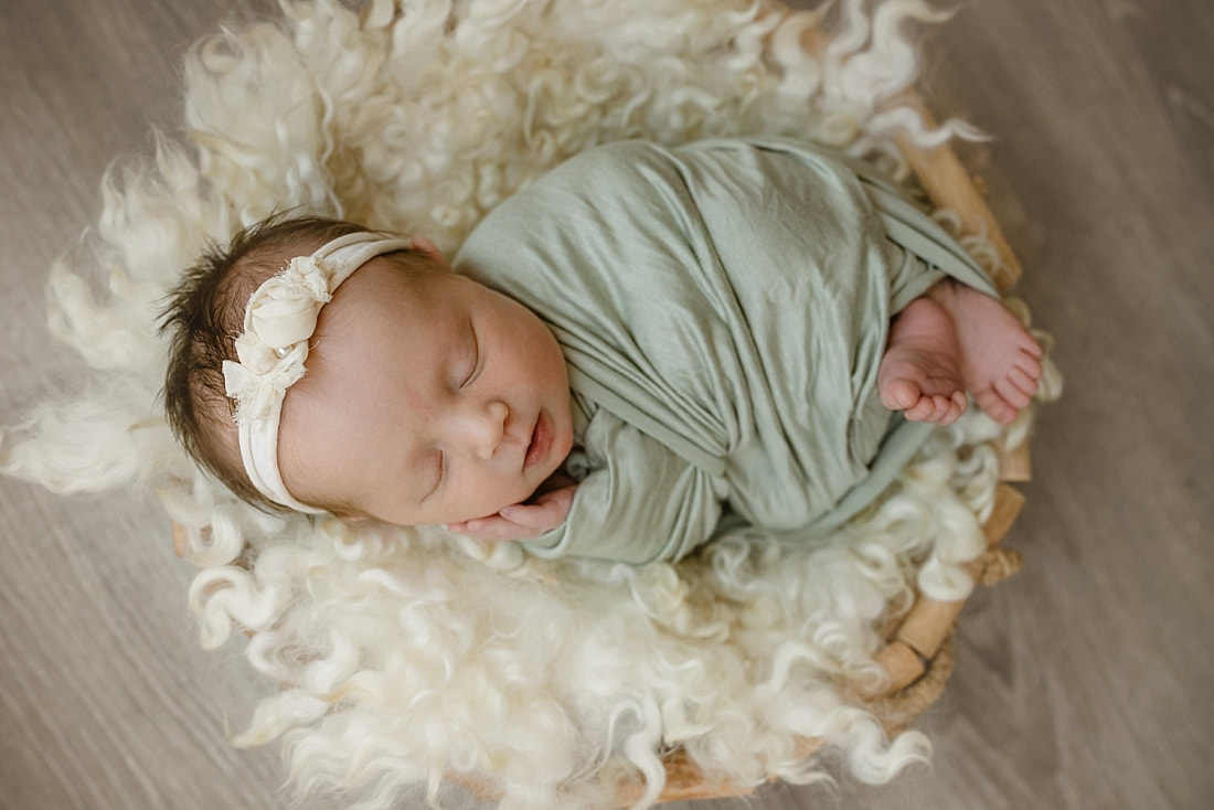 baby girl wrapped in green, sleeping in basket for newborn photos in Memphis, TN
