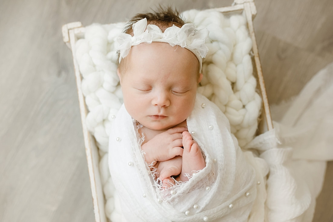 baby girl wrapped in white blanket, sleeping in basket for newborn photos in Memphis, TN