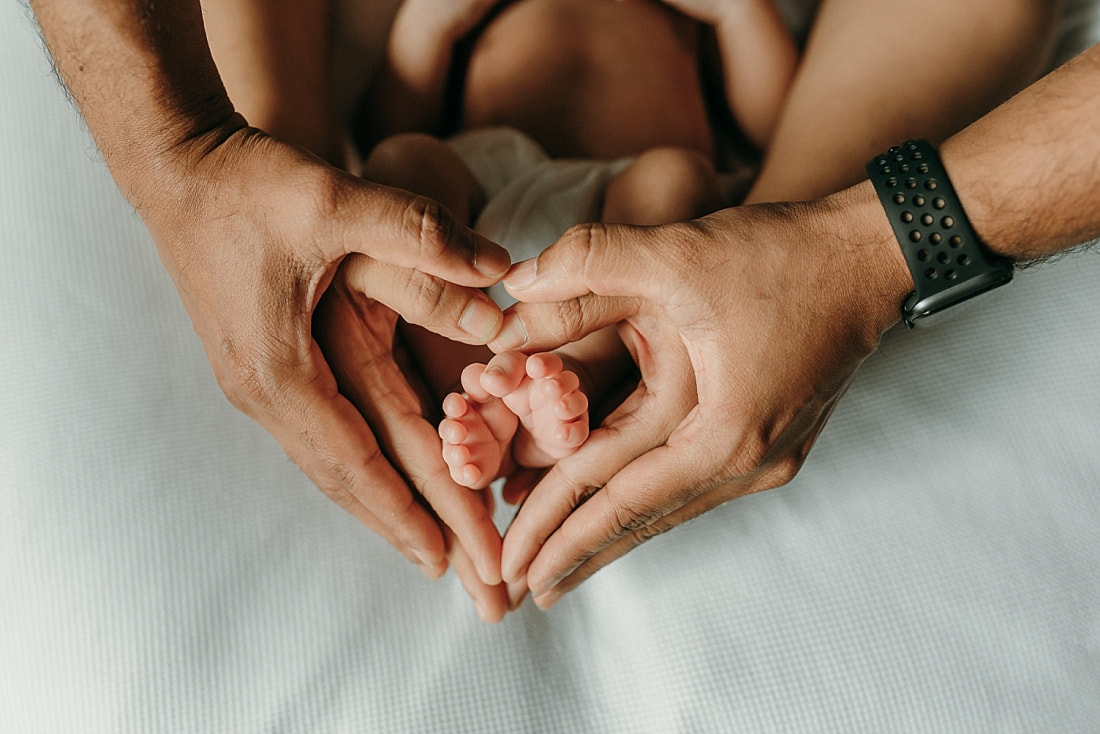 mom and dad's hands making a heart around newborn baby's toes in memphis, TN