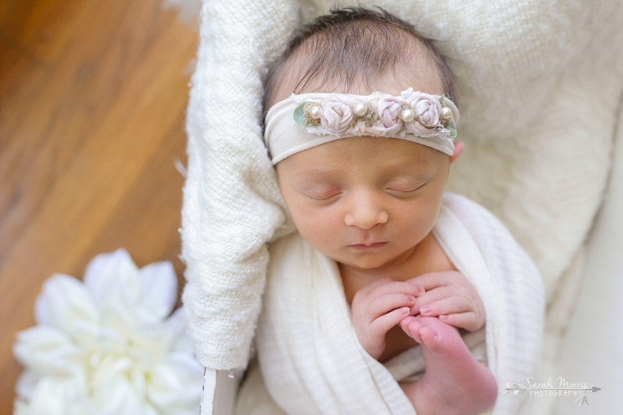 Newborn Photography | Newborn photo of baby girl posed in a white wooden box with white flowers at her Newborn Photo Session in Memphis, TN