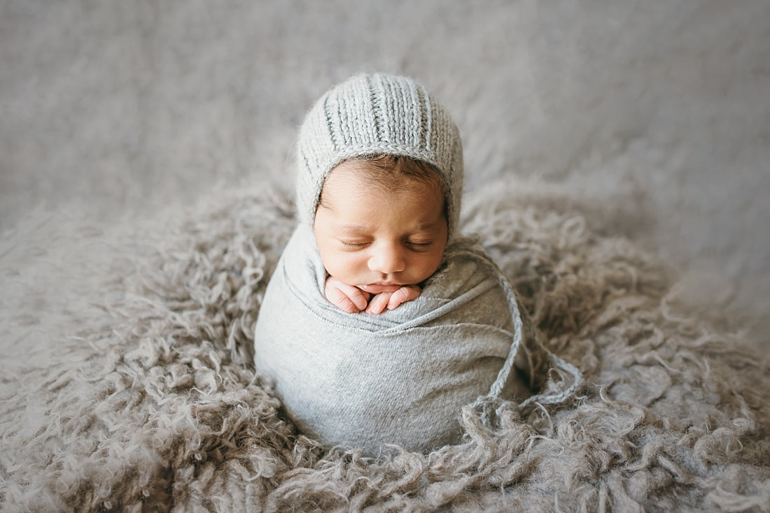 newborn baby boy wearing knit bonnet and swaddled in soft blanket during newborn session in memphis tn