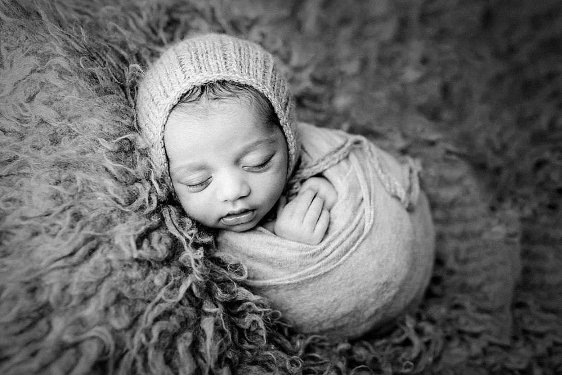 newborn baby boy wearing knit bonnet and swaddled in soft blanket during newborn session in memphis tn