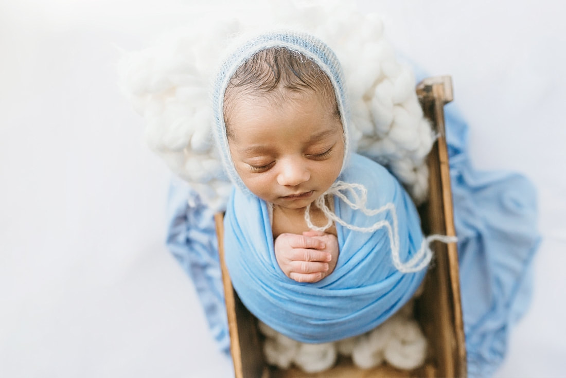 newborn baby boy wrapped in blue wearing knit blue bonnet for newborn photos in memphis